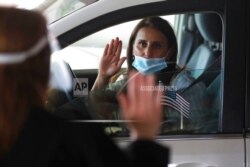 In this June 26, 2020 photo, U.S. District Judge Laurie Michelson, left, administers the Oath of Citizenship to Hala Baqtar during a drive-thru naturalization service in Detroit.