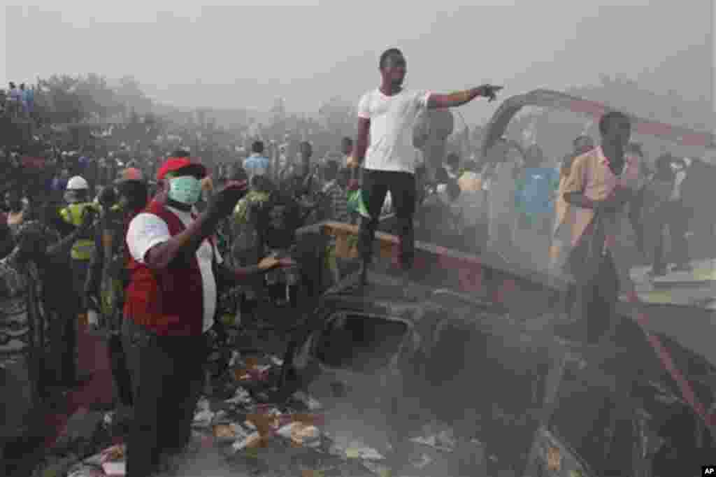 Onlookers stand near a crashed passenger plane in a neighborhood just north of Murtala Muhammed International Airport, in Lagos, Nigeria, Sunday, June 3, 2012.