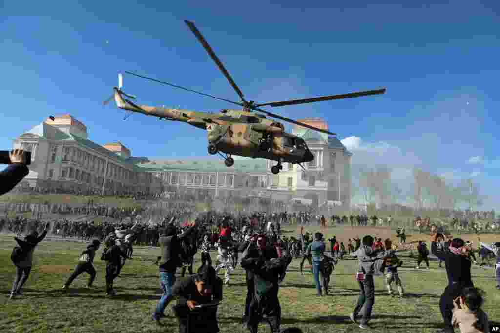 A military helicopter flies over people during the Afghan Security Forces Exhibition, at the Darul Aman Palace in Kabul.