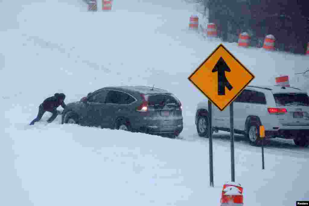 A man tries to push a vehicle stuck in the snow on the New York State Thruway near Nyack, a northern suburb of New York City, March 14, 2017.