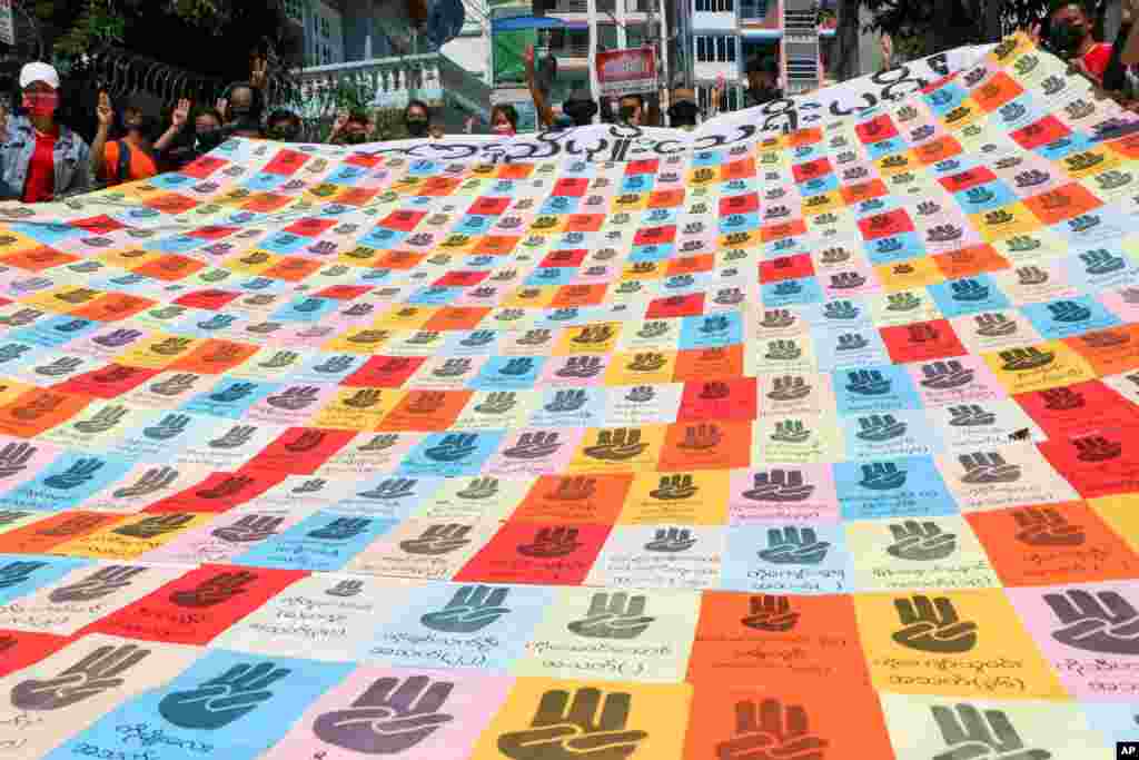 Demonstrators hold a banner with the symbolic three-finger salute and names of those who were killed during anti-coup protests in Kamayut township of Yangon, Myanmar.