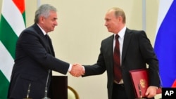 Russian President Vladimir Putin (r) and leader of Georgia's breakaway province of Abkhazia Raul Khadzhimba shake hands at a signing ceremony in the Bocharov Ruchei residence in Sochi, Russia, Nov. 24, 2014.