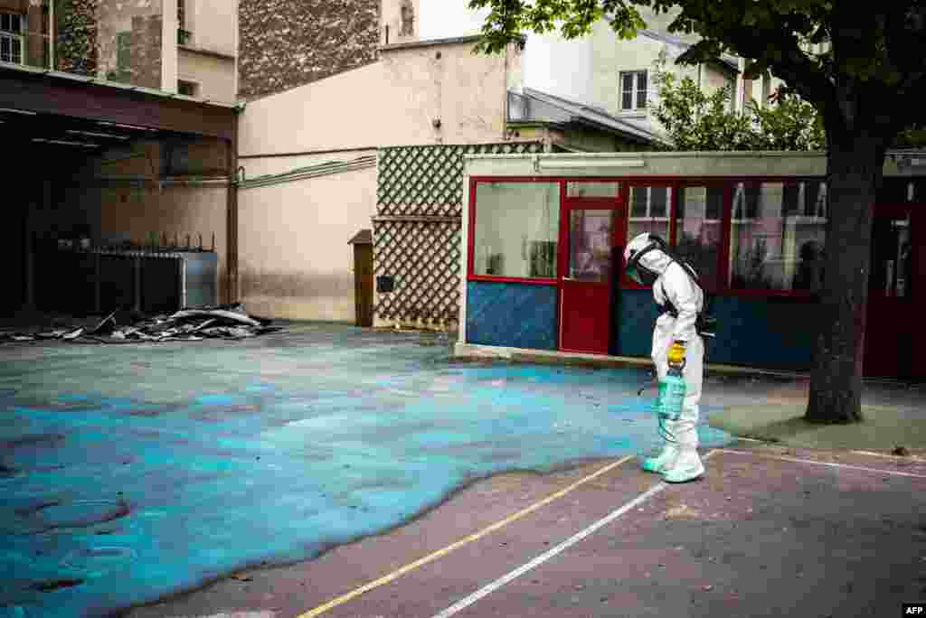 A worker sprays a substance on the ground to soak up lead during an operation at Saint Benoit school near Notre-Dame cathedral in Paris, France.
