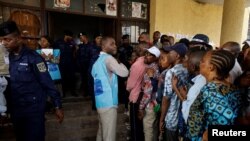 An election official calms down angry voters, who have been waiting to cast their ballots, outside a polling station during the presidential election, in Kinshasa, the Democratic Republic of Congo December 20, 2023.