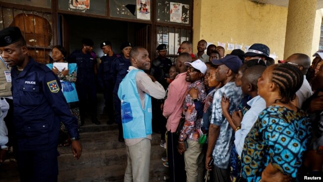 An election official calms down angry voters, who have been waiting to cast their ballots, outside a polling station during the presidential election, in Kinshasa, the Democratic Republic of Congo December 20, 2023.