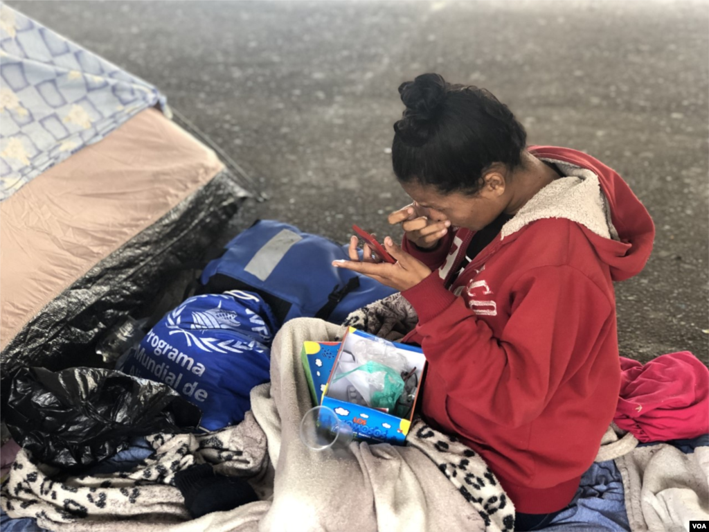 Una mujer venezolana se mira en un espejo mientras trata de maquillarse. Ipiales, Colombia, 11 de septiembre de 2019. Foto: Celia Medoza - VOA. 