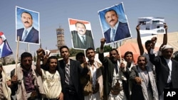 Yemeni men hold up portraits of President Ali Abdullah Saleh as they celebrate his return to Sana'a after more than three months of medical treatment in Saudi Arabia, even as his forces were battling dissident troops in the capital, September 23, 2011.