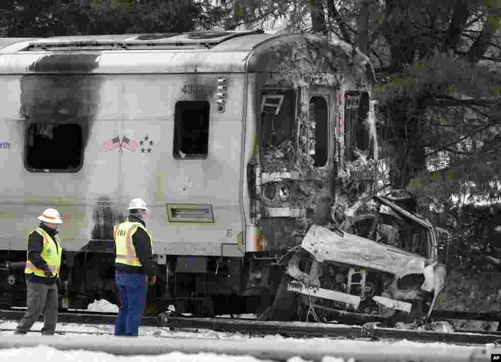 Authorities wearing Federal Railroad Administration vests look over the wreckage of a Metro-North Railroad train and a SUV in Valhalla, New York. Five passengers and the SUV&rsquo;s driver were killed in the crash in Valhalla, about 20 miles north of New York City. Authorities said the impact was so forceful the electrified third rail came up and pierced the train.