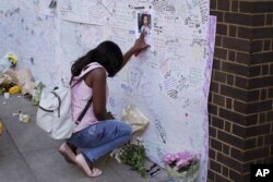 A woman touches a missing poster for 12-year-old Jessica Urbano on a tribute wall after laying flowers on the side of Latymer Community Church next to the fire-gutted Grenfell Tower in London, June 16, 2017.