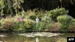 FILE - A woman takes a photo of Nympheas in the French Impressionist painter Claude Monet's gardens (Jardins de Claude Monet) in in Giverny, northwestern France, on Aug. 29, 2024.