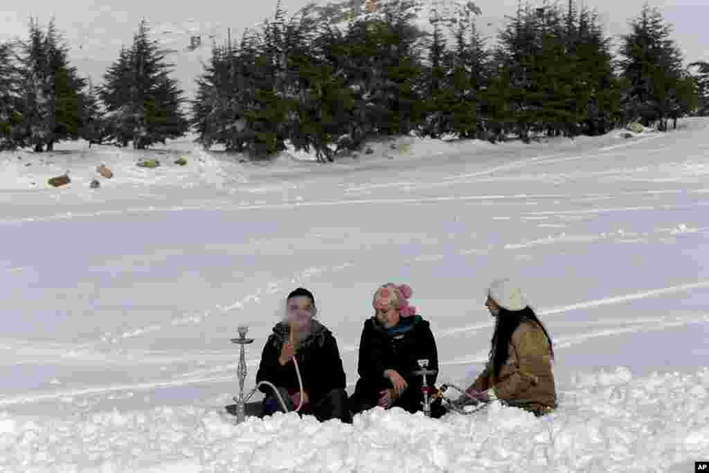 Lebanese sit in the snow as they smoke a water pipe a day after a strong snow storm, near the village of Hamana, Mount Lebanon, Feb. 22, 2015.