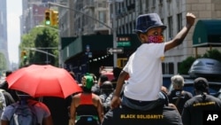 A man carries a child as they march near Central Park, during a Juneteenth celebration, June 19, 2020, in New York. Juneteenth commemorates when the last enslaved African Americans learned they were free 155 years ago.