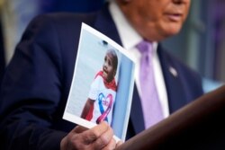 FILE - President Donald Trump holds a photo of LeGend Taliferro during a news conference in the James Brady Press Briefing Room at the White House, Aug. 13, 2020.