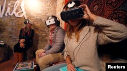 Members of the media try earphones and a headset used for virtual reality at the Sundance Film Festival in Park City, Utah, Jan. 23, 2015. 