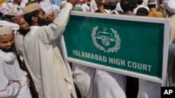 FILE - Men are seen outside the Islamabad High Court, Oct. 11, 2011, in Islamabad, Pakistan. The court this week temporarily barred the extradition of Talha Haroon, 19, wanted by American authorities in connection with allegedly hatching a terror plot. 