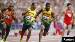 Jamaica's Yohan Blake (2nd R) takes the baton from teammate Michael Frater (2nd L) next to Netherlands' Giovanni Codrington (L) during the men's 4x100m relay round at the Olympic Stadium, August 10, 2012. 