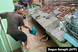 Warga berupaya mengungsi saat terjadi banjir besar di kawasan Jatinegara, Jakarta pada 4 Maret 2025. (Foto: Bagus Saragih/AFP)