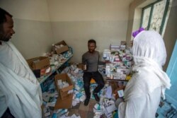 A pharmacist, center, speaks to patients as he sits among the packages of medicine able to be recovered in Hawzen, in the Tigray region of northern Ethiopia, May 7, 2021. The hospital was damaged and looted by Eritrean soldiers, witnesses said.