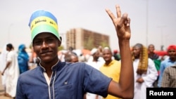 FILE - A Sudanese demonstrator flashes victory sign during a protest against the army's announcement that President Omar al-Bashir would be replaced by a military-led transitional council, in Khartoum, Sudan, April 12, 2019. 