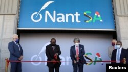 Le président sud-africain Cyril Ramaphosa (C-L) et le milliardaire américain d'origine sud-africaine Patrick Soon-Shiong ont coupé le ruban lors du lancement de NantSA, une future usine de fabrication de vaccins, au Cap, en Afrique du Sud, le 19 janvier 2022.