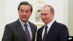 Russian President Vladimir Putin, right, shakes hands with Chinese Foreign Minister Wang Yi during their meeting in Moscow, Russia, March 11, 2016.