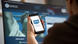 FILE - Woman holding smartphone with ESTA Electronic System for Travel Authorization logo sign, filling form to travel to the United States under the Visa Program. (Adobe Stock)