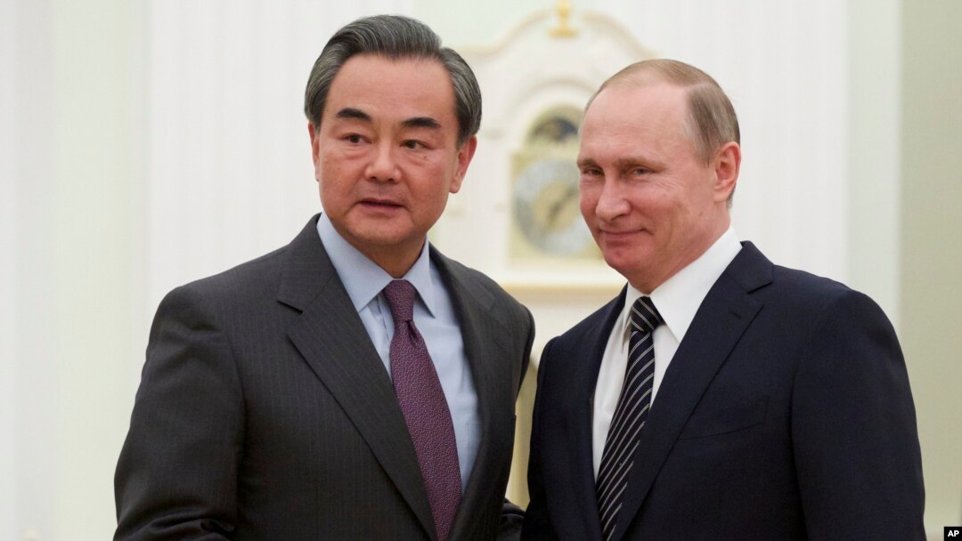 Presiden Rusia Vladimir Putin (kanan) berjabat tangan dengan Menlu China Wang Yi di Moskow, Rusia (11/3).