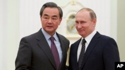 Presiden Rusia Vladimir Putin (kanan) berjabat tangan dengan Menlu China Wang Yi di Moskow, Rusia (11/3).