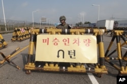 Binh sĩ Hàn Quốc đứng canh phía sau chướng ngại vật trên chiếc cầu dẫn đến vùng phi quân sự, gần làng biên giới Bản Môn Điếm.