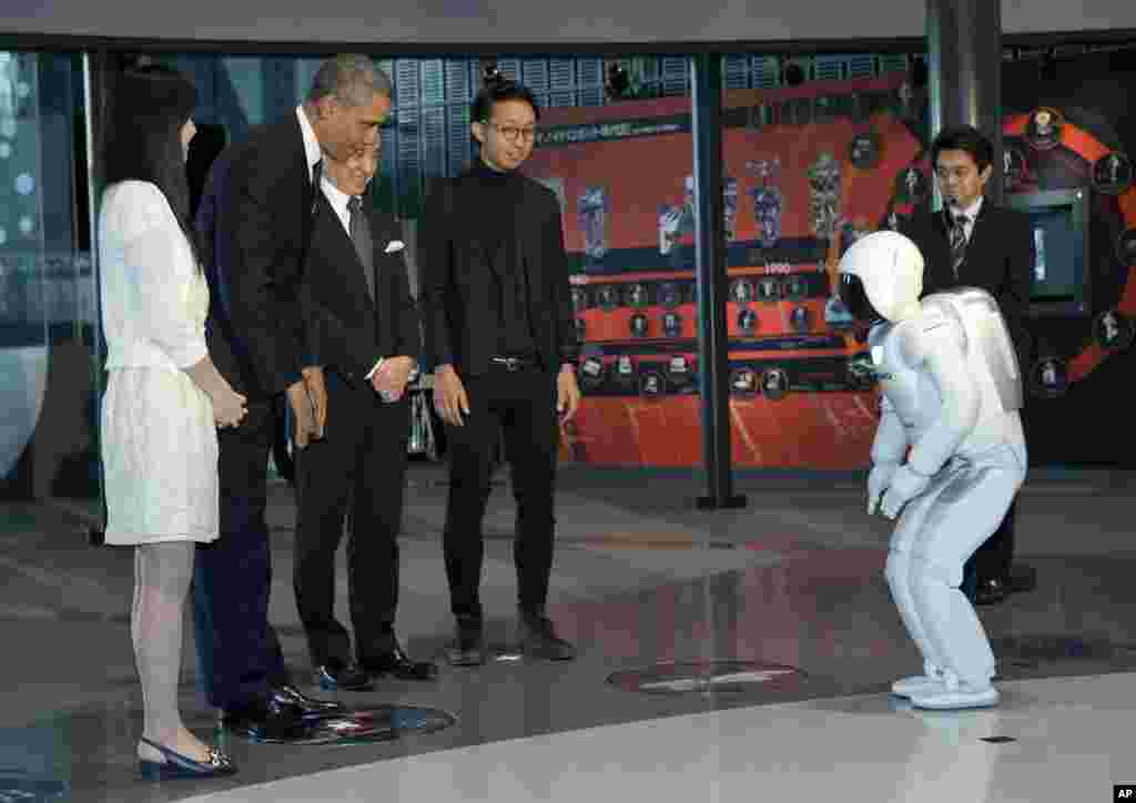 O Presidente Barack Obama e ASIMO, um acrónimo do projecto de inovação Advanced Step/ Innovative MObility, cumprimentam-se durante um evento de ciência jovem no Museu Nacional de Ciência e Inovação Emergente em Tóquio, Abril 24, 2014.