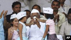 Children wearing traditional Indian caps bearing the words: "I am Anna", offer coconut water and honey to veteran Indian social activist Anna Hazare (C) after he ended his fast at Ramlila grounds in New Delhi, August 28, 2011