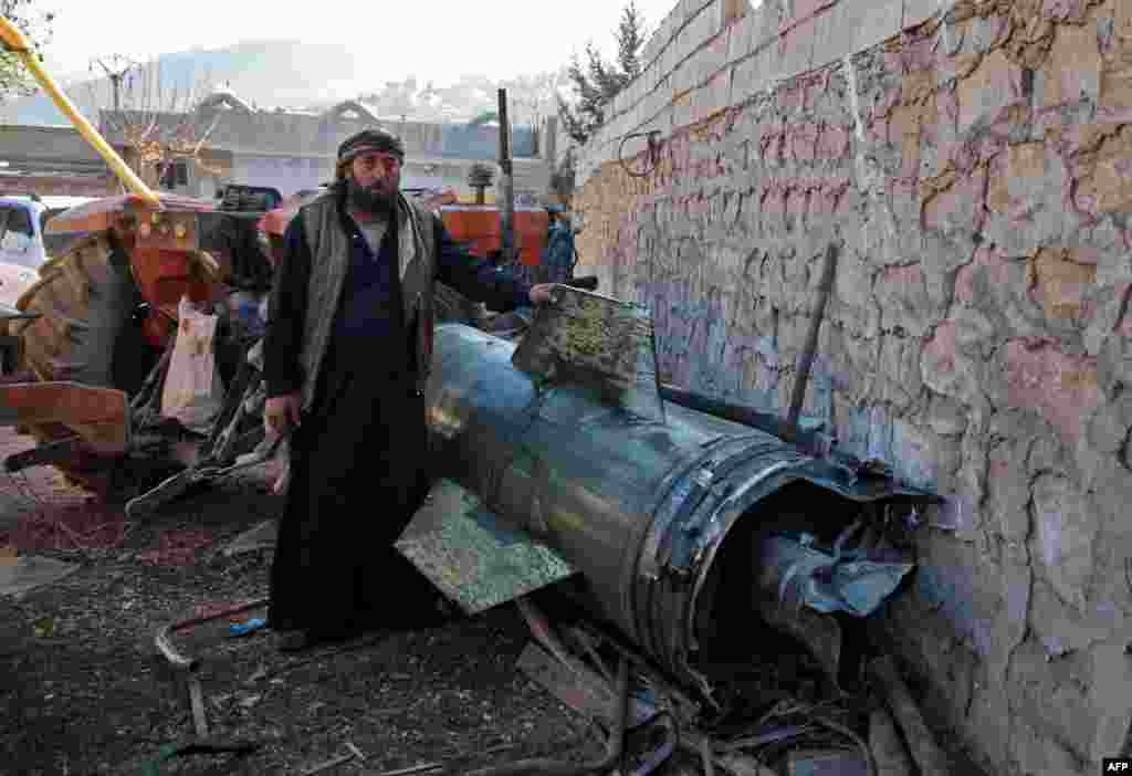 A man stands next to a piece of a ground-to-ground missile fired by government forces. The missile hit a temporary camp in the village of Qah near the Turkish border in the northwestern Idlib province, Syria.