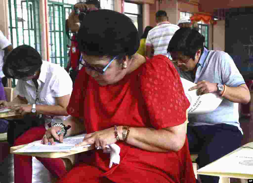 Former Philippine First Lady Imelda Marcos (C), wife of former President Ferdinand Marcos, fills out her ballot together with her children Senator Ferdinand Jr. "Bongbong" Marcos (R) and Irene Marcos Araneta during the Philippines' midterm elections.