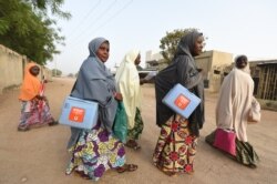 FILE - Health workers walk from house to house in search of children to immunize during vaccination campaign against polio at Hotoro-Kudu, Nassarawa district of Kano, in northwest Nigeria, April 22, 2017.