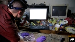An FBI computer analyst examines the computer of suspected child webcam cybersex operator David Timothy Deakin, from Peoria, Illinois, during a raid at his home in Mabalacat, Philippines, April 20, 2017.