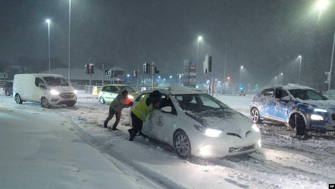 Sejumlah warga tampak mendorong mobil yang terjebak di jalanan bersalju di Leeds, Inggris, pada 5 Januari 2025. (Foto: Danny Lawson/PA via AP)
