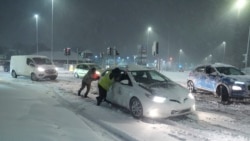 Sejumlah warga tampak mendorong mobil yang terjebak di jalanan bersalju di Leeds, Inggris, pada 5 Januari 2025. (Foto: Danny Lawson/PA via AP)