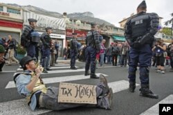 French gendarmes stand near an anti G20 demonstrator who takes part in protest against globalization and tax havens, at the French-Monaco border in Cap d'Ail, November 3, 2011.