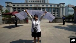 2013年8月21日，一名女子在濟南中級人民法院前抗議。對薄熙來的審判引來一些抗議和上訪者，有人挺薄，也有人借機訴說自己的冤情