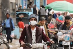 A man wears a protective face mask as he rides a motorcycle amid fears of the spread of the coronavirus disease (COVID-19) in Sana'a, March 16, 2020.
