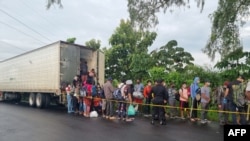 Migrantes que viajan en un camión de carga en un intento de llegar a la frontera con los Estados Unidos se bajan luego de que el camión fuera detenido por la Policía Nacional Civil de Guatemala (PNC), en Mazatenango, Guatemala. (Foto VOA / Archivo)