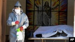 یک مامور بهداشت اطراف یک تابوت در سن حوزه در بولیوی را ضد عفونی می کند. ۱۶ ژوئیه ۲۰۲۰