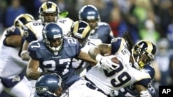 St. Louis Rams' Steven Jackson runs the ball as Seattle Seahawks' Jordan Babineaux (27) and Kentwan Balmer (95) attempt the tackle in the first half of an NFL football game, 2 Jan. 2011, in Seattle.