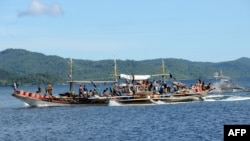 FILE - Philippine fishermen aboard their motorized boat sail along Ulugan Bay, in Puerto Princesa, Palawan island, south of Manila before heading to the open sea facing south China sea to fish.