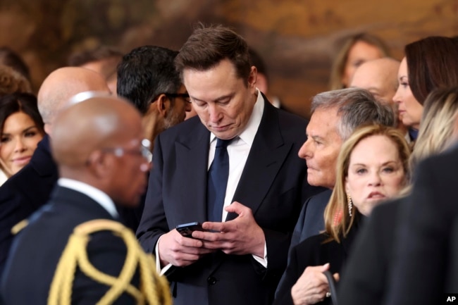 Elon Musk menggunakan telepon selulernya setelah Pelantikan Presiden ke-60 di Rotunda Gedung Capitol AS di Washington, Senin, 20 Januari 2025. (Kevin Lamarque via AP)