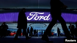 FILE - Attendees walk by the Ford display at the North American International Auto Show in Detroit, Jan. 11, 2016. 