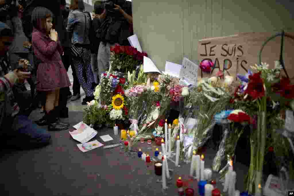 A girl prays outside the French Embassy in Lima, Peru, during a ceremony honoring the victims of the attacks in Paris, Nov. 15, 2015.