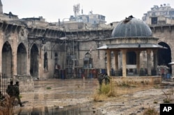 This photo released by the Syrian official news agency SANA shows Syrian troops and pro-government gunmen inside the destroyed Grand Umayyad mosque in the old city of Aleppo, Syria, Dec. 13, 2016. Government forces and rebel fighters have fought to control the 12th-century mosque in the last four years, until Syrian troops seized control of it this week.