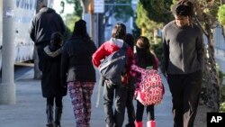 FILE - Parents pick up their children from school early, on Tuesday, Dec. 15, 2015, in Los Angeles. Students in Miami, Fort Lauderdale and Houston are heading to school Thursday, hours after school officials in those cities received threats similar to the ones received by the Los Angeles and New York school districts earlier this week.