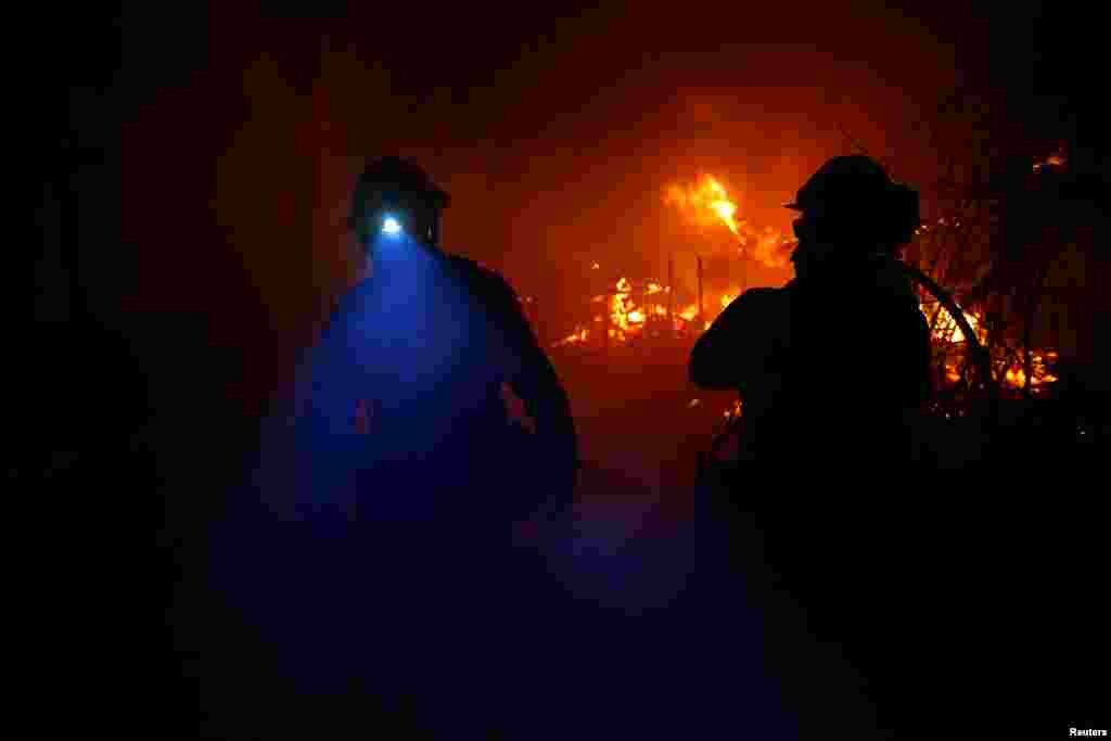 Bomberos luchan contra el incendio Woolsey Fire en Malibu, Calif., Nov. 9, 2018. El fuego destruyó decenas de estructuras, obligó a miles de evacuaciones y cerró una importante autopista.